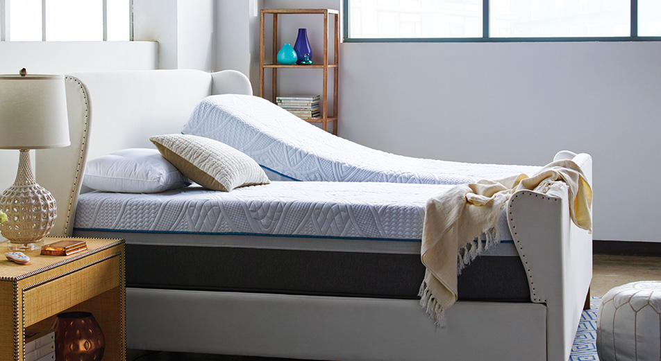 adjustable Sealy Posturepedic mattress on a white bed frame in a large room